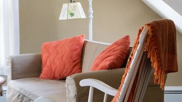 A cozy room with a white chair, a brown sofa, and a lamp.
