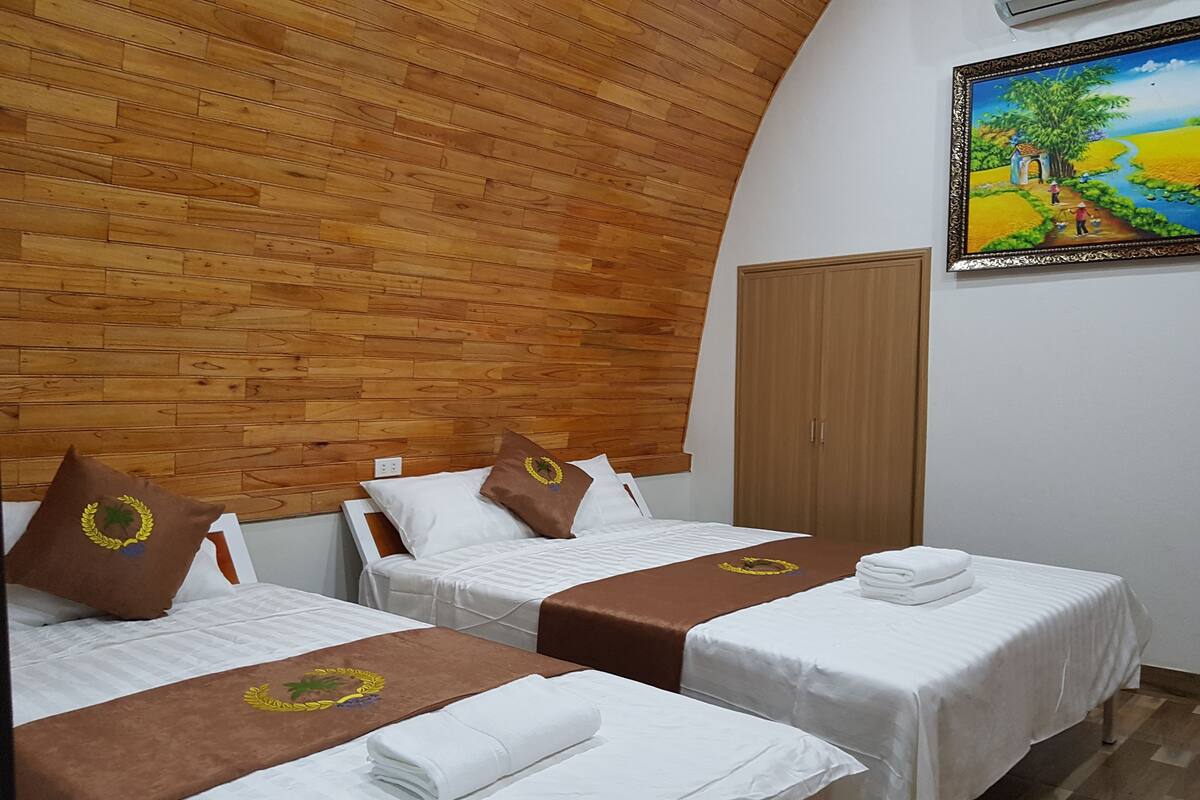 A hotel room with two beds, wooden ceiling, and a painting on the wall.