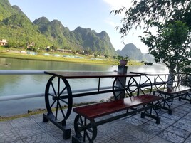 Un banco junto al río con vistas a un río tranquilo y colinas verdes al fondo.