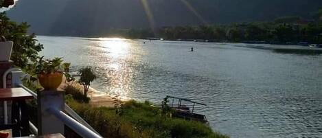 A lakeside view with mountains in the background, a wooden deck, and a railing.
