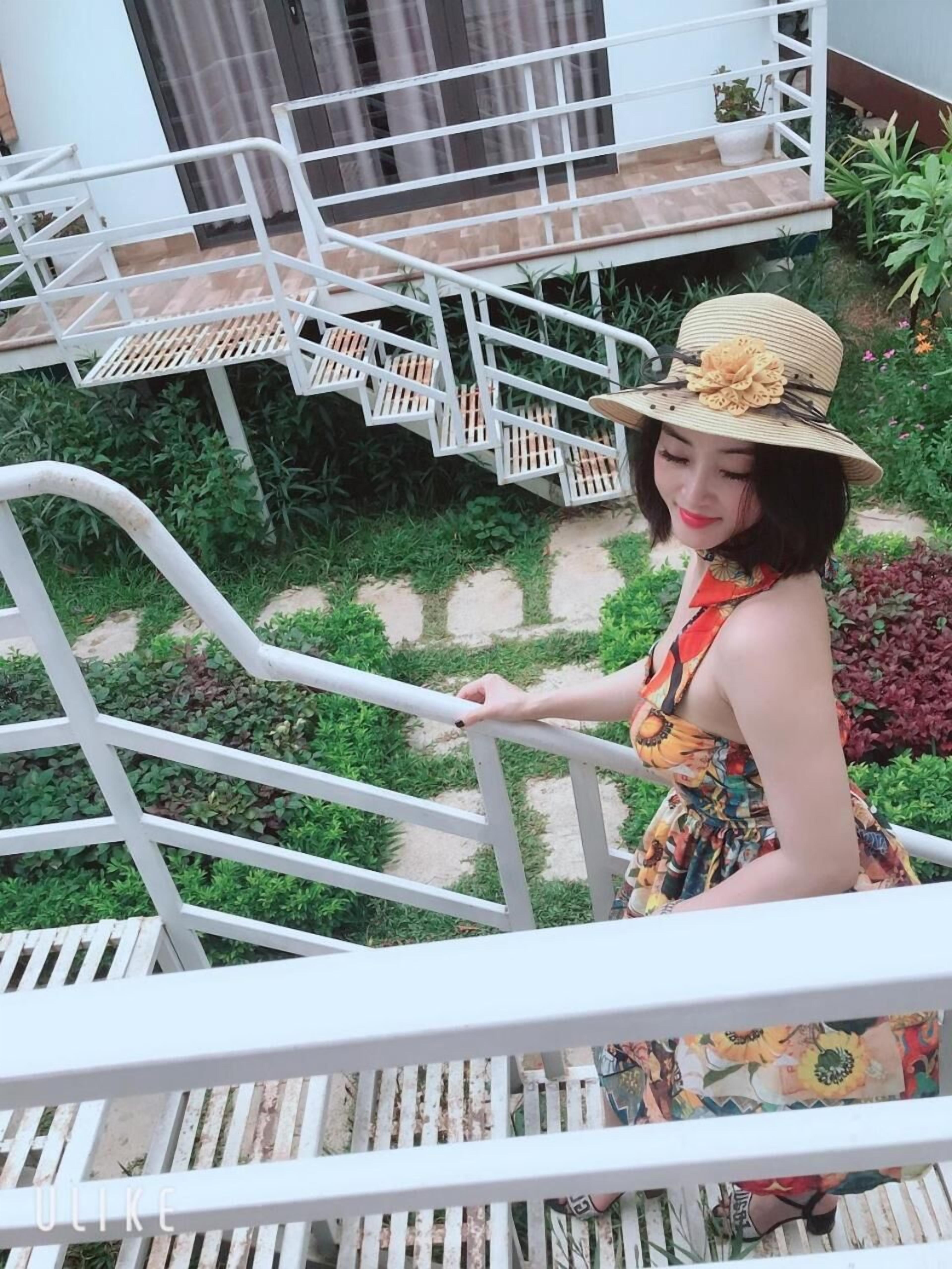A woman on a white metal staircase with a garden view.
