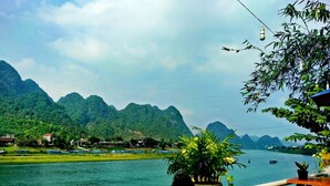 A view from a balcony overlooking a river with mountains in the background. - Areca Bungalow (Phong Nha)