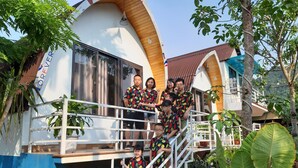 A group of people on a balcony of a building with a curved roof and a sign that reads "FOREVER". - Areca Bungalow (Phong Nha)