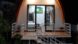 A cozy, semi-open structure with a wooden arch and a balcony. Inside, there is a bed, a chair, and a painting on the wall. - Areca Bungalow (Phong Nha)