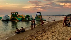 Una playa con juegos inflables y gente relajándose en la arena.