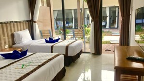 Habitación de hotel con dos camas, una mesa de madera y vista al exterior.