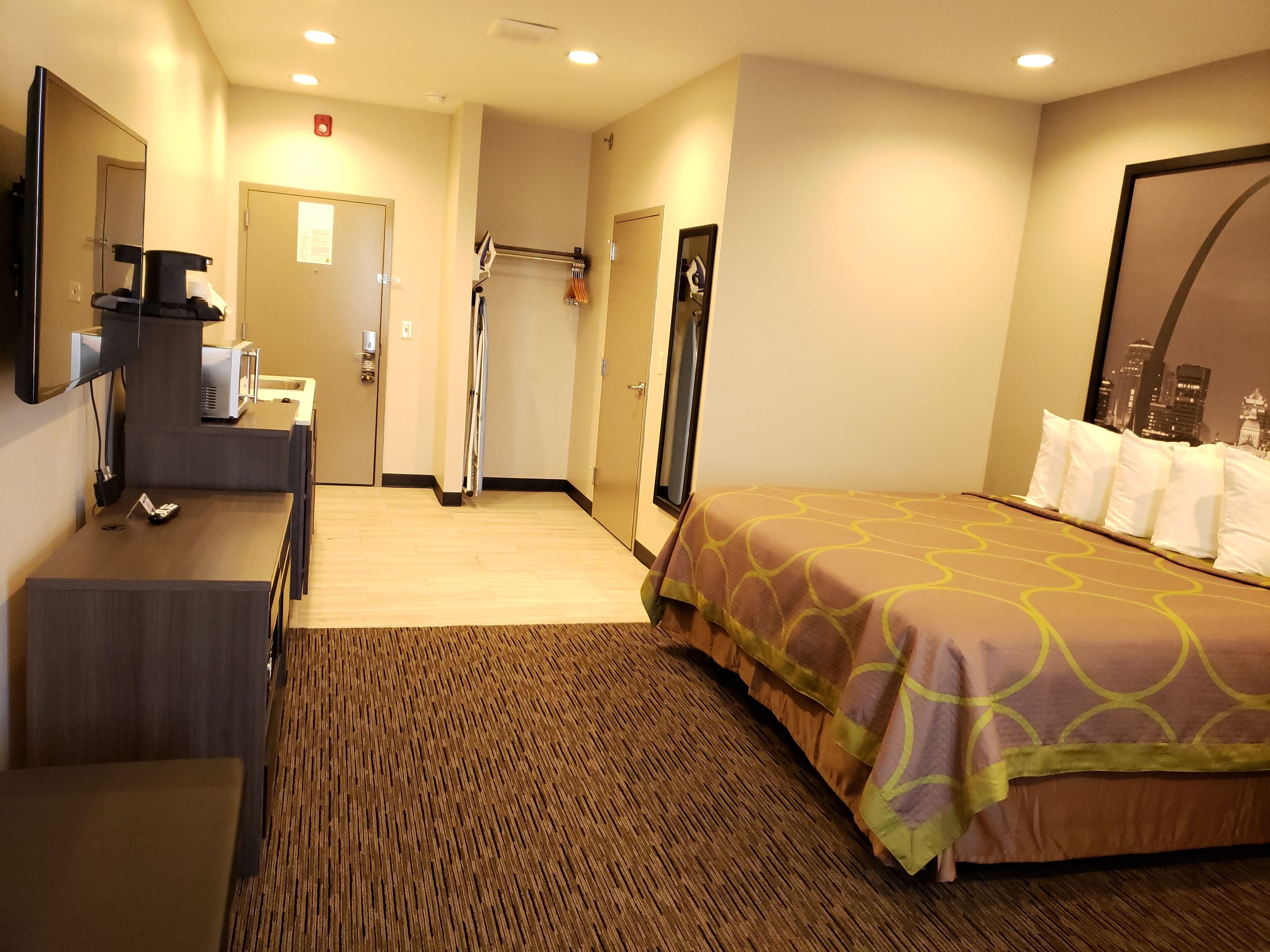 A hotel room with a bed, a desk, a mirror, and a door leading to a bathroom.