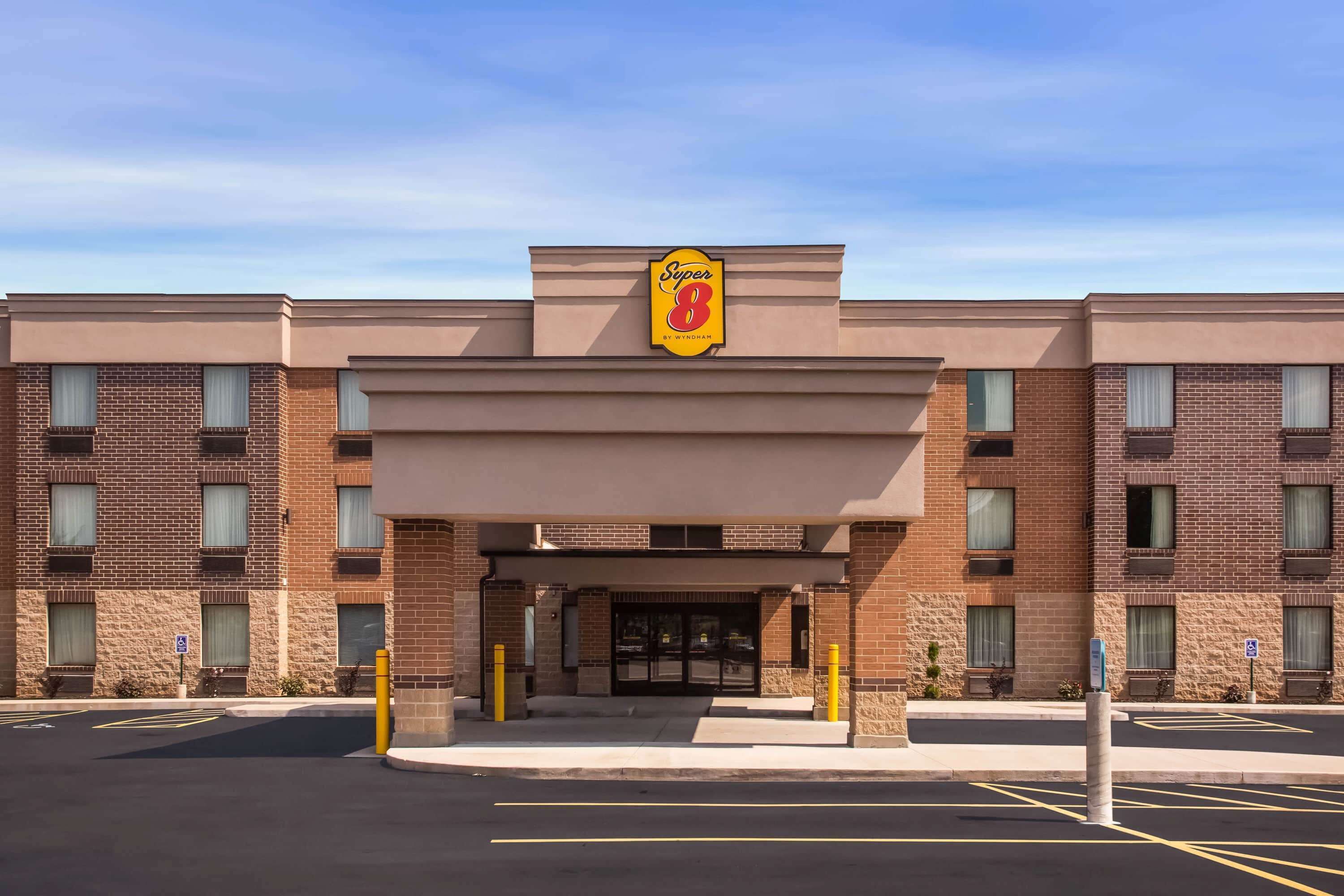 A Super 8 hotel entrance with a brick facade, double doors, and a clear sky.
