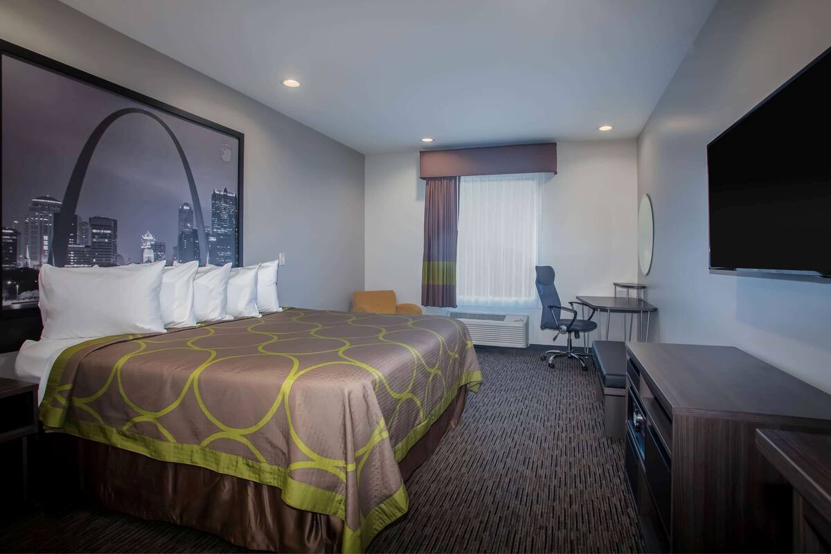 Une chambre d’hôtel avec un grand lit, un bureau, une chaise et un téléviseur.