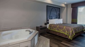 A modern hotel room with a large bed, a separate bathroom with a bathtub, and a cityscape view through the window.