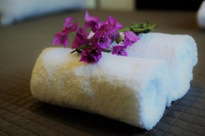 A rolled towel with a purple flower on a textured surface. - Verdeoliva Bed & Breakfast (Bari)