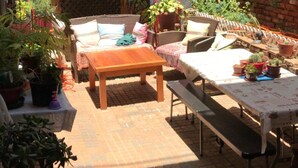 Un patio al aire libre con mobiliario de mimbre, un mural y plantas en macetas.
