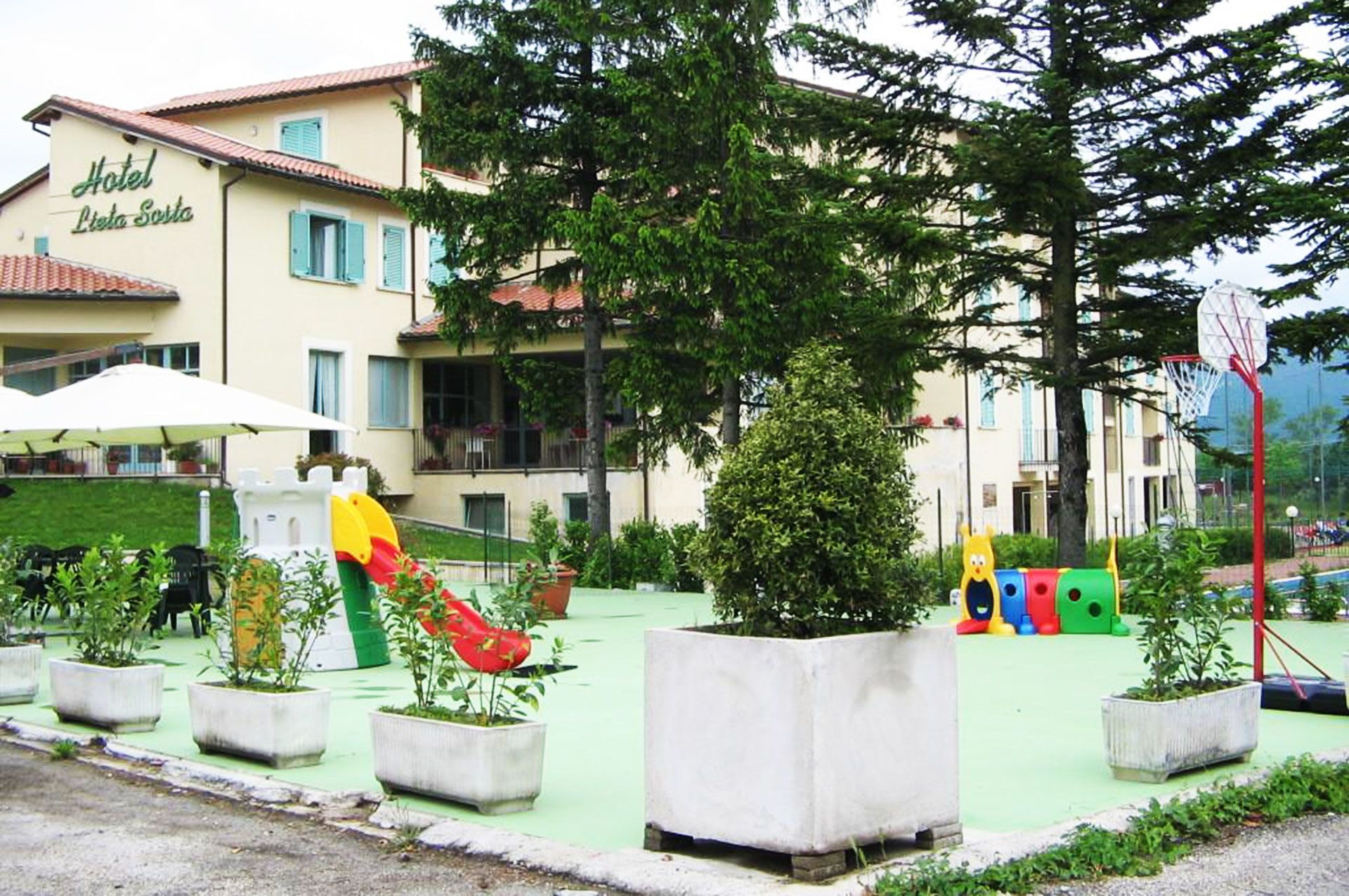 Un hotel llamado "Hotel Lieta Sosta" con un área de juegos que incluye toboganes y estructuras recreativas.