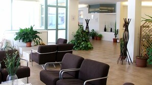 A modern interior with a seating area, potted plants, and a kitchen in the background. - Lieta Sosta (Foligno)
