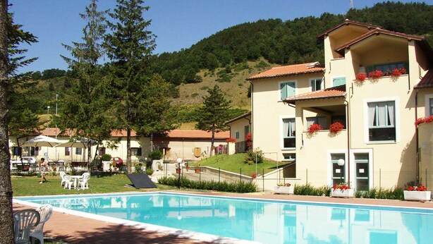 A hotel with a swimming pool, outdoor seating, and a hillside backdrop. - Lieta Sosta (Foligno)
