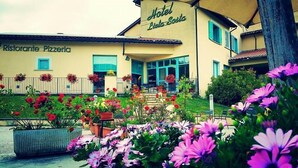 A building with a sign for 'Hotel Leila Sota' and 'Ristorante Pizzeria'. There are flower beds in front of the building. - Lieta Sosta (Foligno)