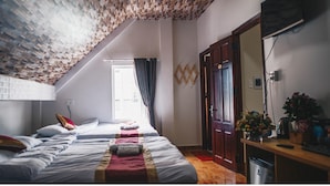 A bedroom with a sloped ceiling, a bed with multiple pillows, a wooden desk, and a mirror. - Villa Homestay Minh Hieu (Lam Vien - Da Lat)