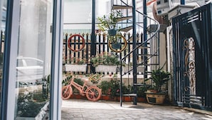 A bicycle parked in a courtyard with a metal gate and potted plants. - Villa Homestay Minh Hieu (Lam Vien - Da Lat)