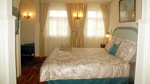 A bedroom with a large bed, a nightstand, a chair, and a chandelier. - Hotel Adler (Sankt Georgen im Schwarzwald)
