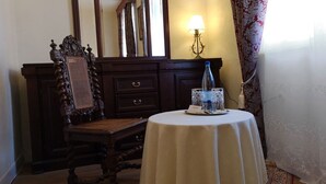 A room with a wooden chair, a table with a white tablecloth, a bottle, and a glass. - Hotel Adler (Sankt Georgen im Schwarzwald)