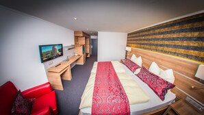 Hotelkamer met een bed, een bureau, een televisie, een rode stoel en een muur met strepen.