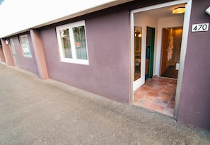 Un edificio de fachada morada, con el número '470' en el lado derecho, y una entrada visible con piso de baldosas que conduce al interior.