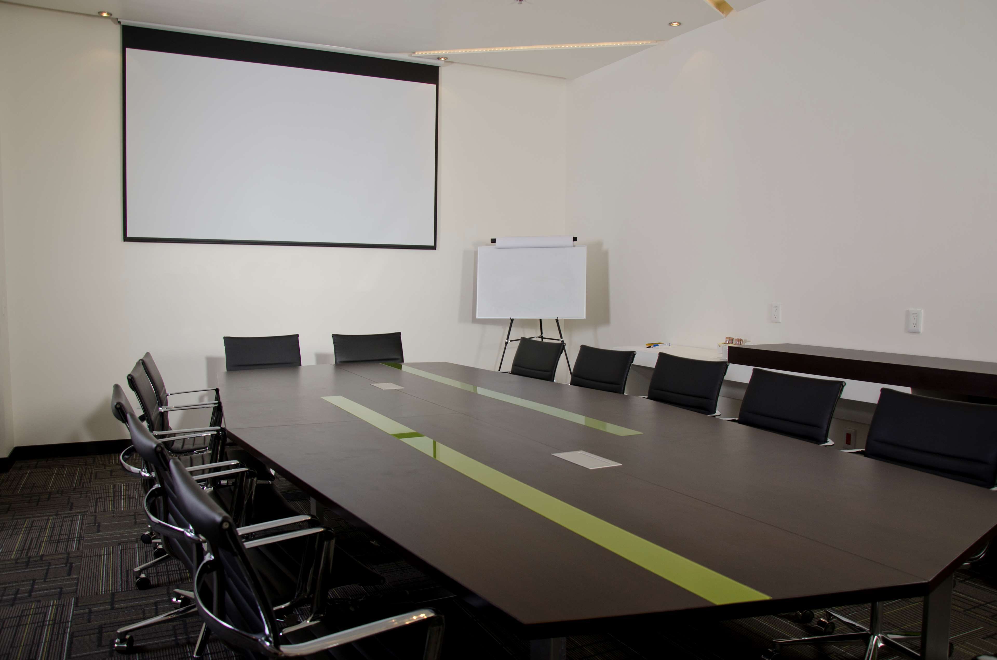 A conference room with a long table, chairs, a projector screen, and a whiteboard.