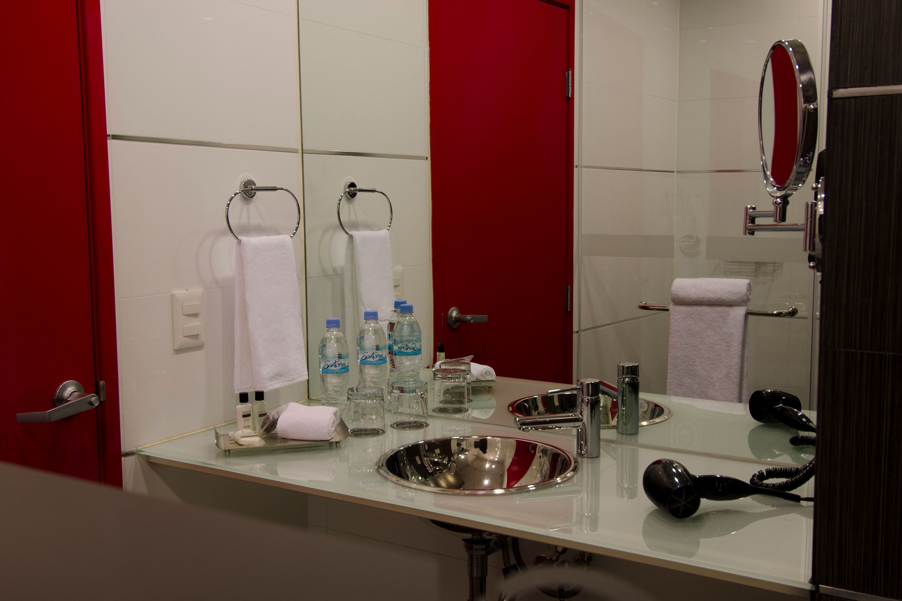 A bathroom with a sink, mirror, towel rack, and hairdryer.
