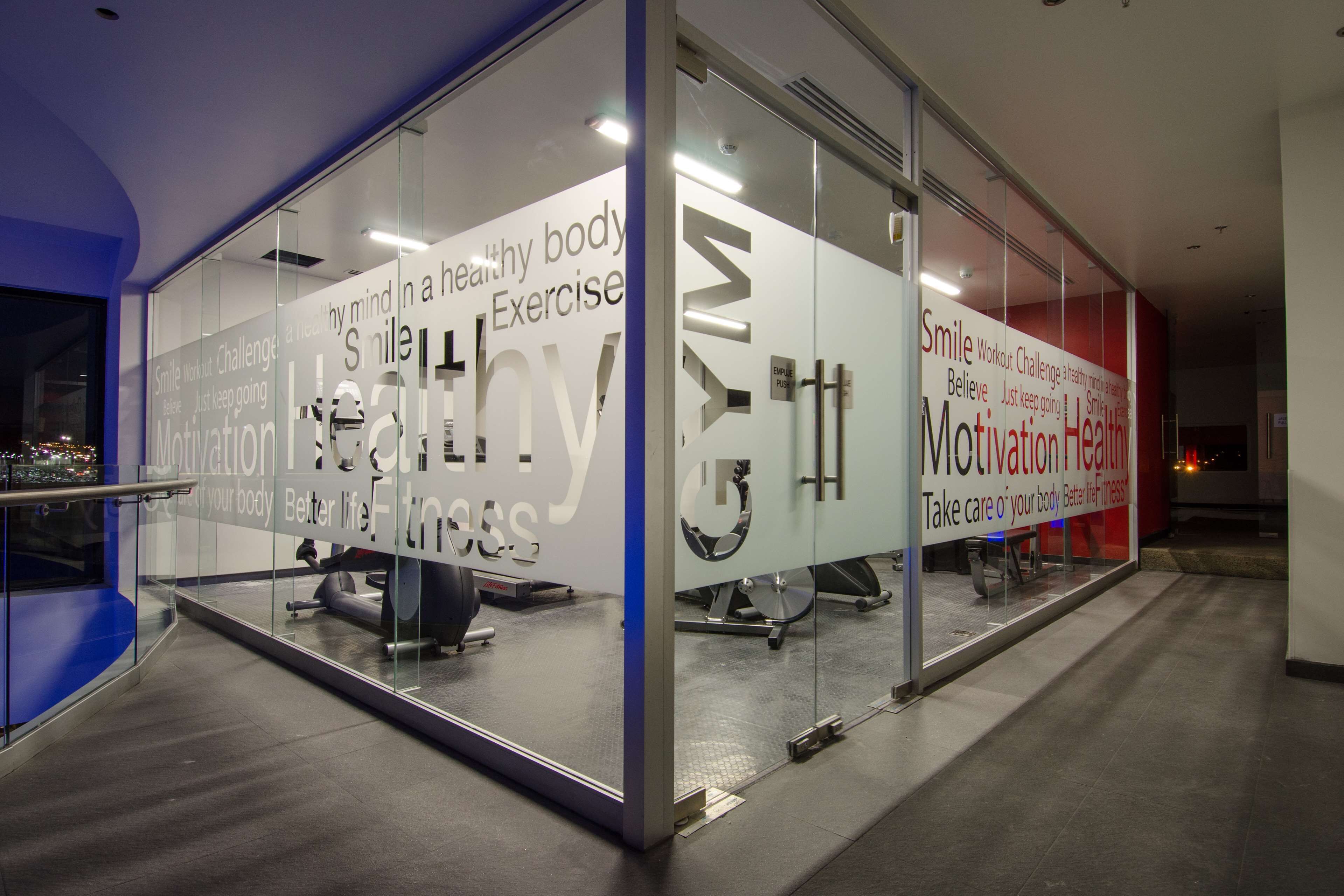 A modern fitness center with motivational wall graphics and exercise equipment.