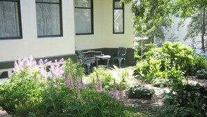 A garden with a brick pathway, a table, and two chairs outside a building with windows and a door. - Guesthouse Sólgarðar (Akureyri)