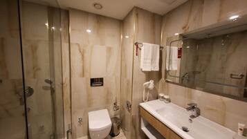 A modern bathroom with a glass-enclosed shower, a white toilet, and a large sink with a mirror above it.