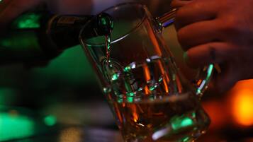 A clear glass mug on a table with a person pouring liquid into it.