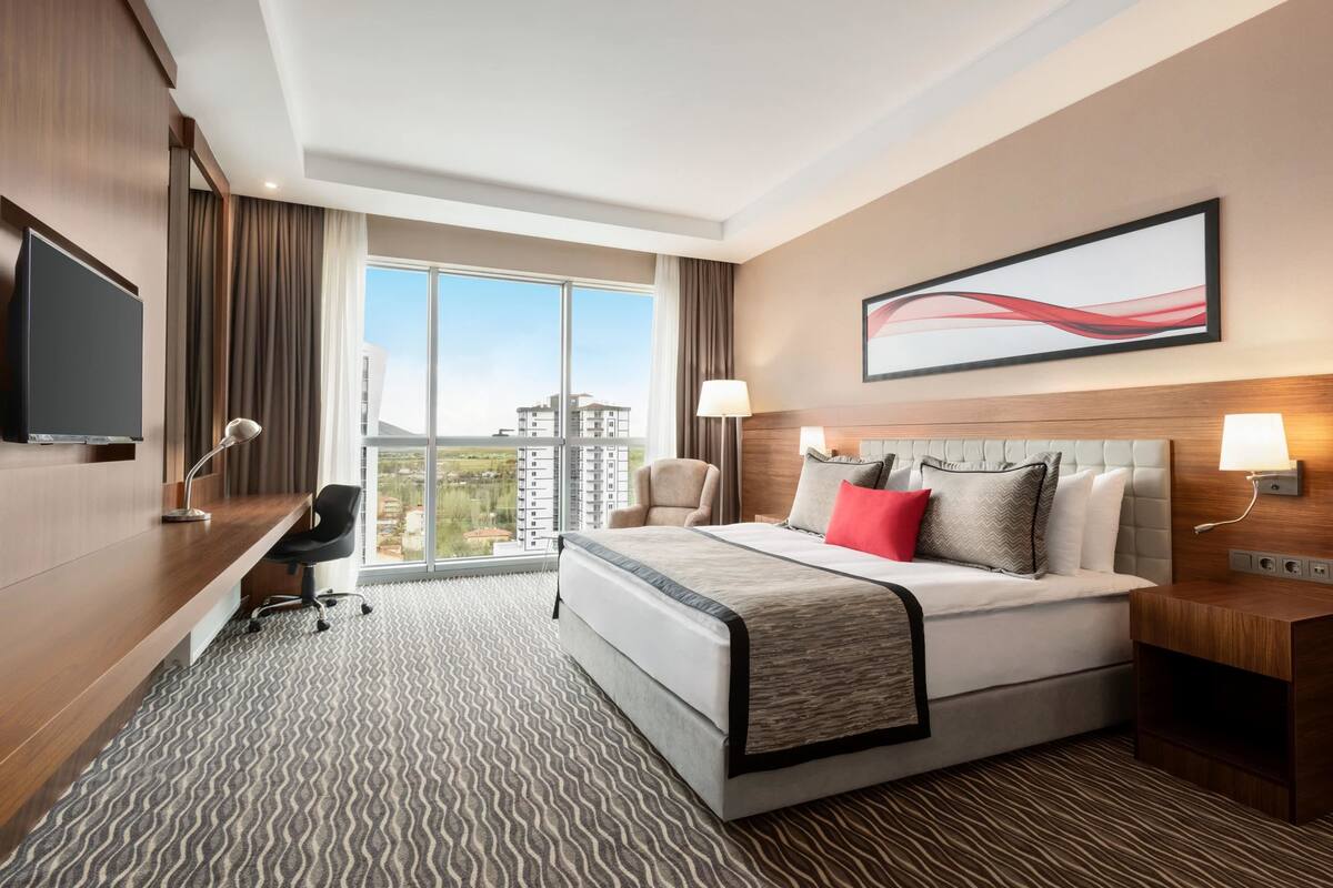 Una habitación de hotel moderna con una cama grande, un escritorio, una silla y un televisor.