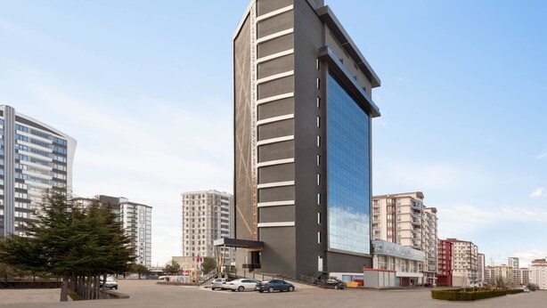 Un hôtel moderne, situé dans un immeuble de grande hauteur, avec une enseigne bien visible au sommet.