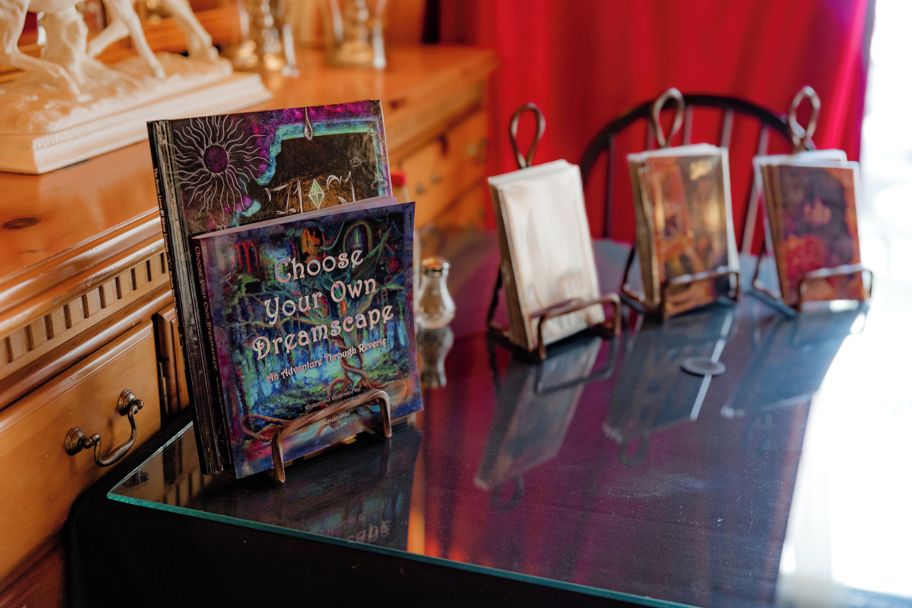 Una mesa con un libro titulado 'Choose Your Own Adventure: The Dragon's Lair' y un recipiente de vidrio decorativo.