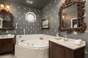 Bathroom features two sinks, a bathtub, and ornate mirrors.