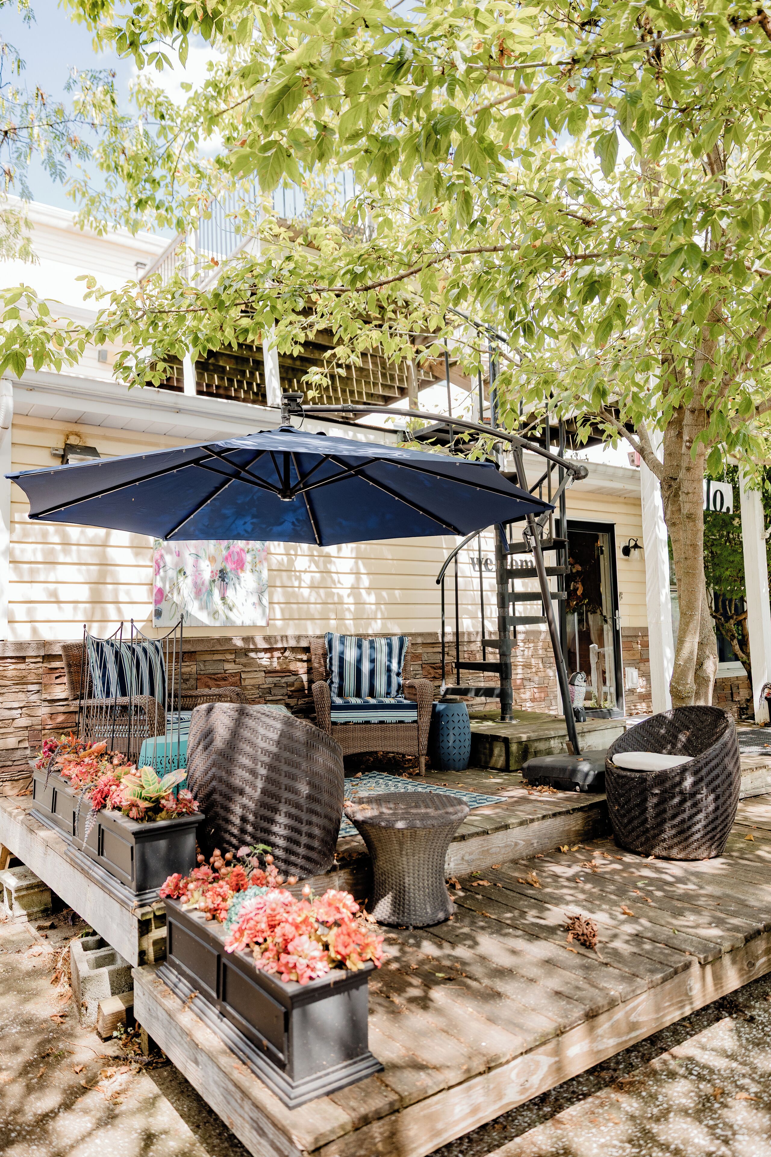 A patio area with outdoor furniture, a large umbrella, and flower planters.
