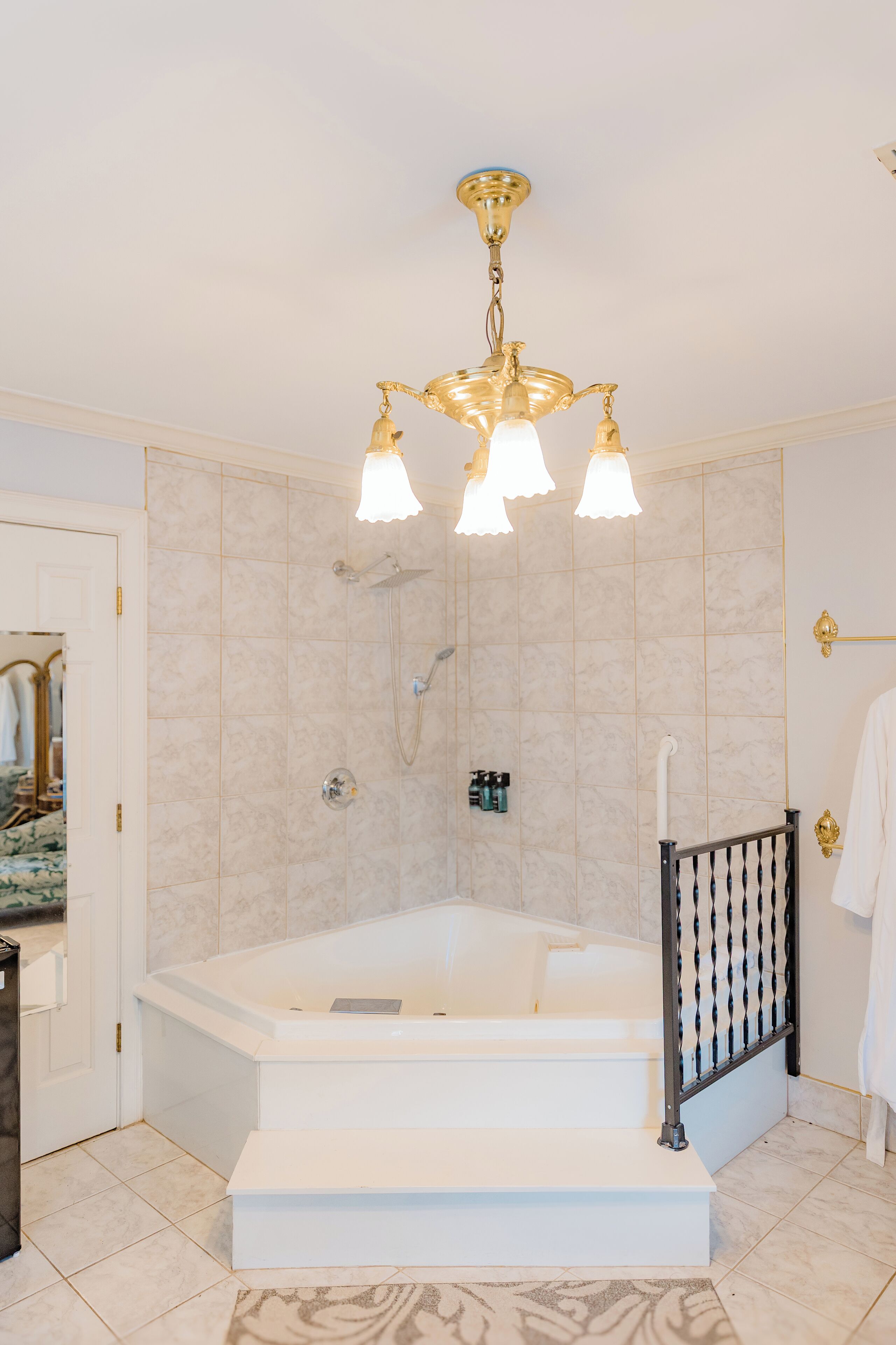 Un baño con una bañera grande, ducha y un candelabro.