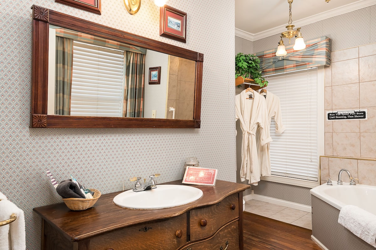Bathroom features a large mirror, sink, bathtub, and glass-enclosed shower area.