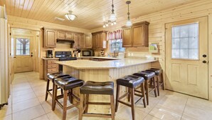 Una cocina amplia con armarios de madera, una isla central con taburetes y un ventanal grande.