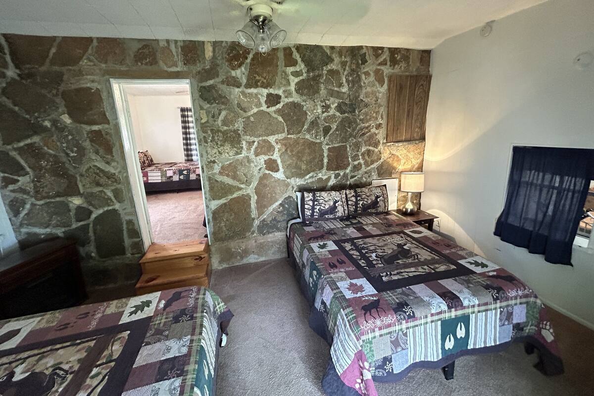 Ein Schlafzimmer mit zwei Betten, einer Steinsäule, einem Deckenventilator und einem Nachttisch mit Lampe.
