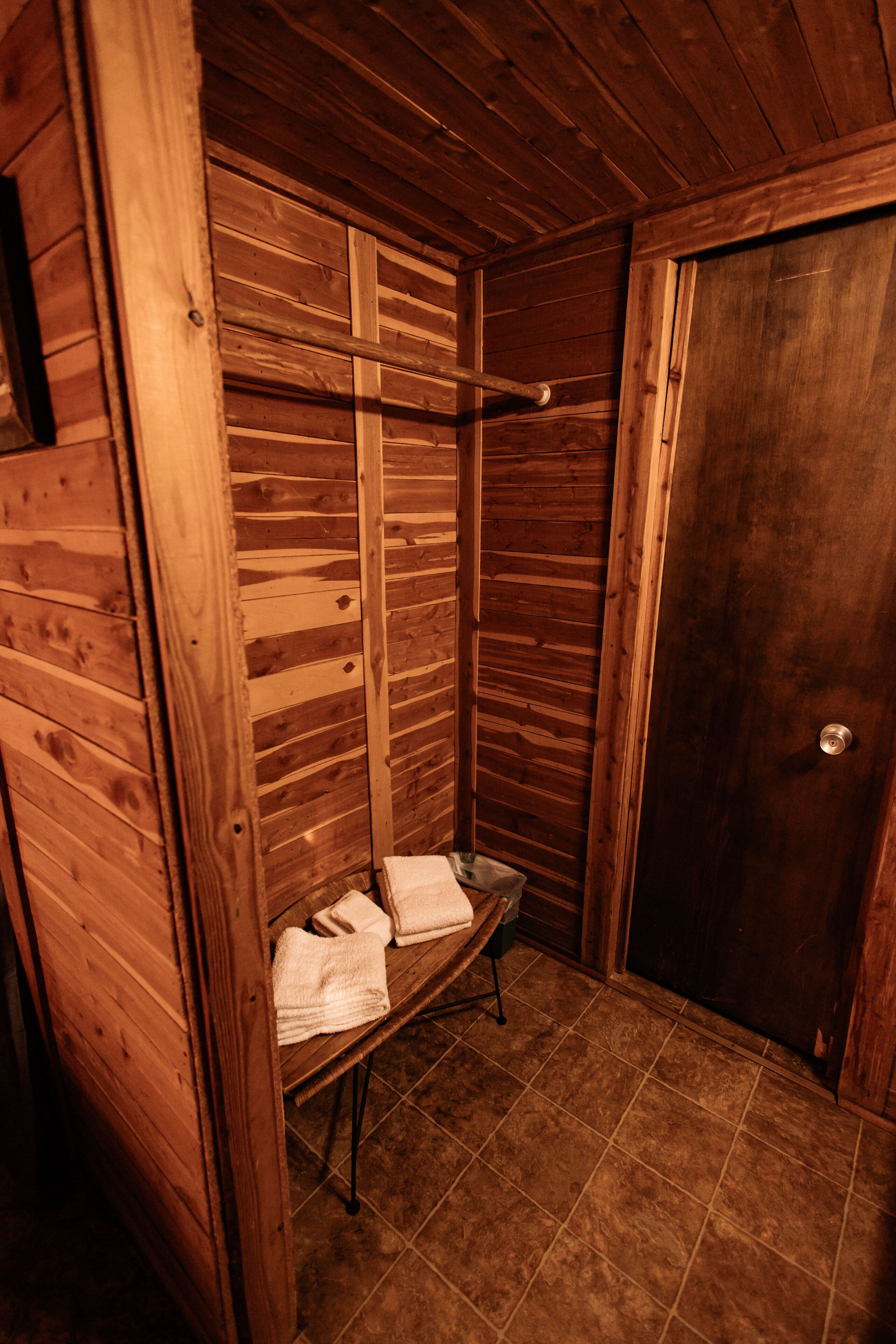 A wooden cabin with a bench, a towel rack, and a door.