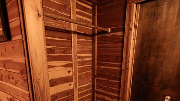 A wooden cabin with a bench, a towel rack, and a door.