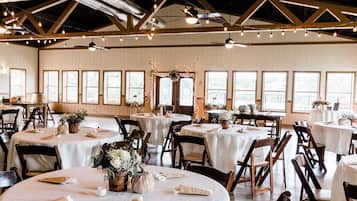 Formal gatherings take place in this elegant space with high ceilings, white paneling, and beautifully set tables.