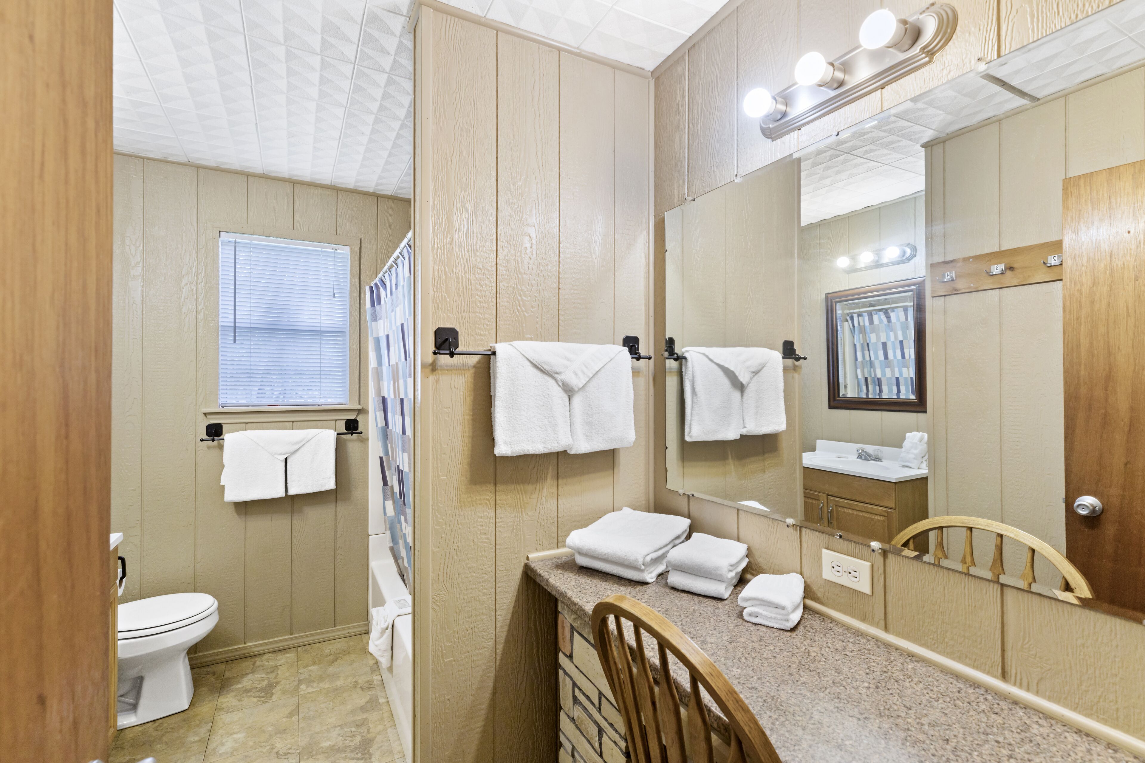 A bathroom with a toilet, sink, mirror, and towel rack.