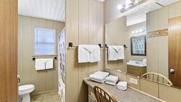 A bathroom with a toilet, sink, mirror, and towel rack.