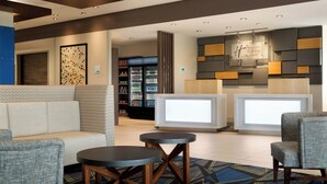 A lobby area with seating, a reception desk, and a refrigerator stocked with beverages.