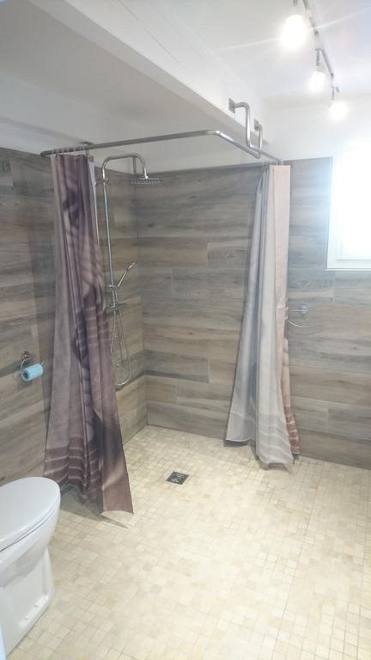 Un baño con ducha, inodoro y pared de madera.