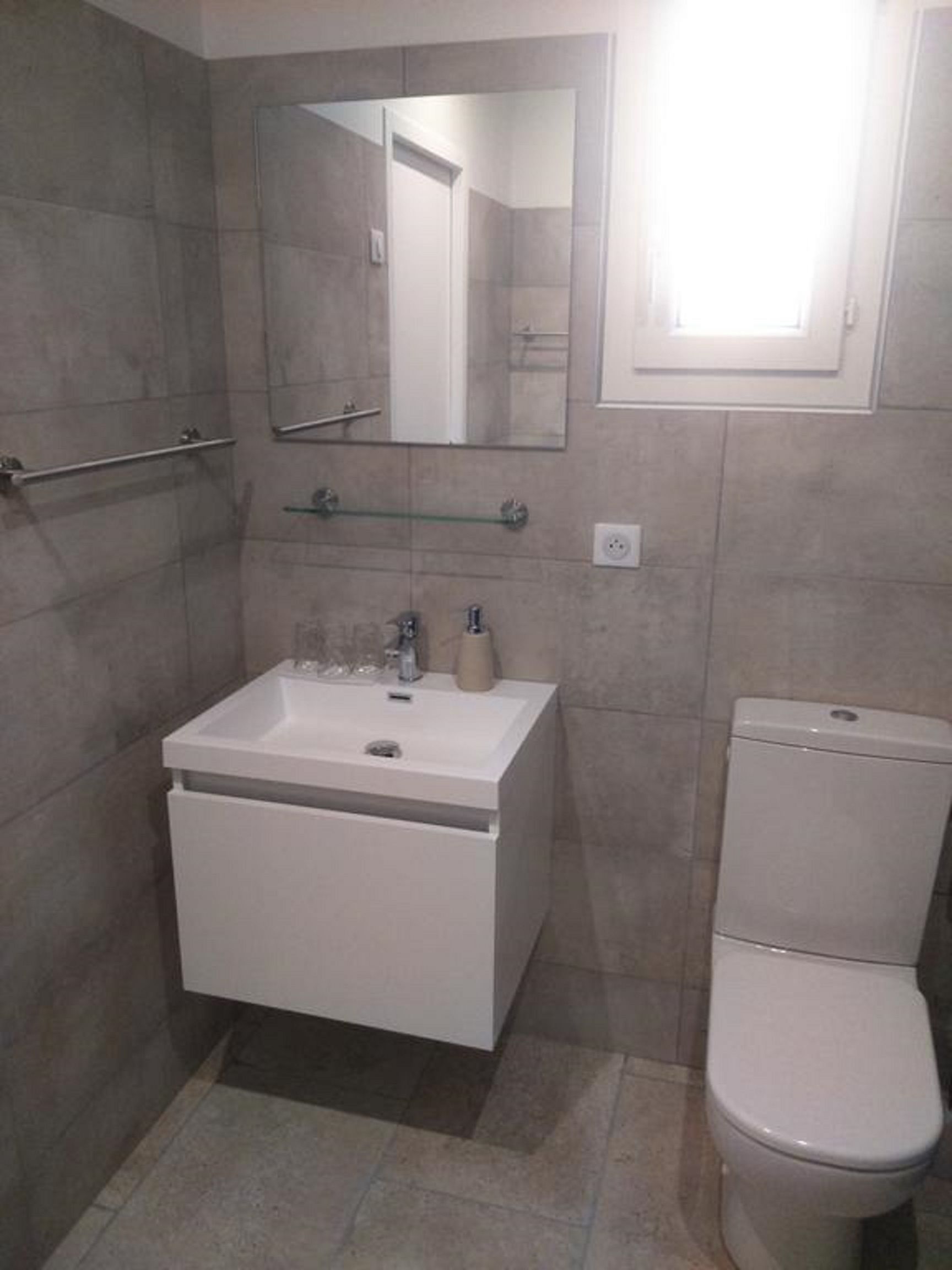 Een badkamer met een witte wastafel, spiegel en toilet.