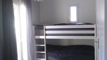A bunk bed room with a window, curtains, and a fluffy white hanging light fixture.